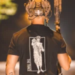black shirt featuring a girl carrying an anti tank weapon.