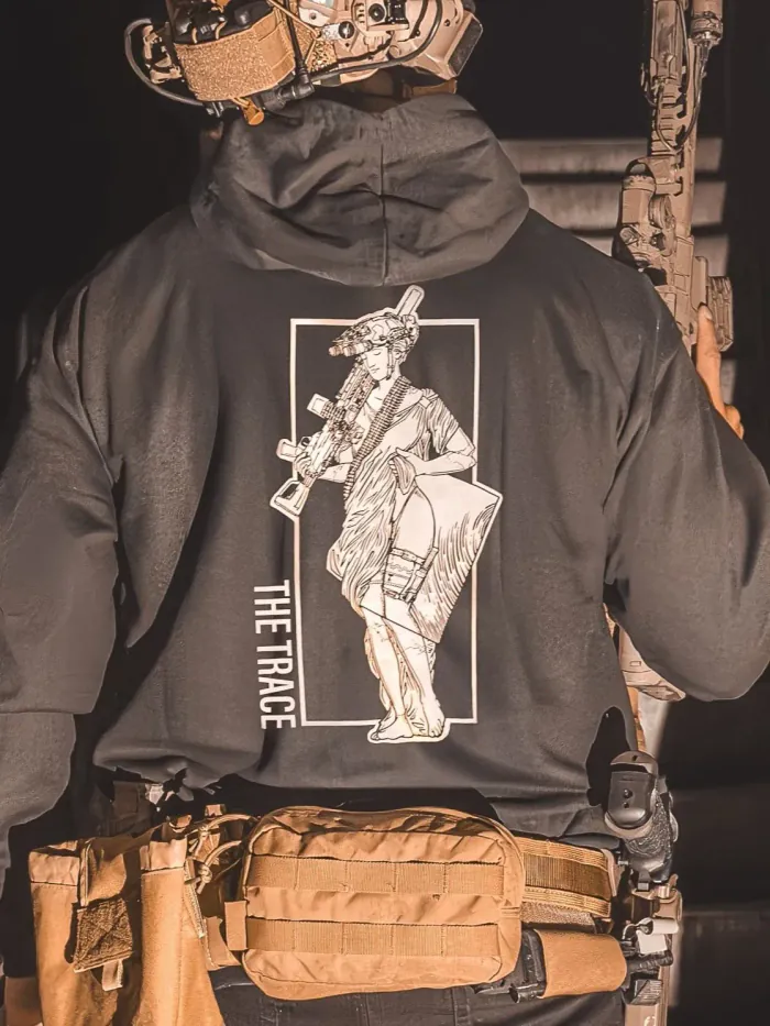 black hoodie from The Trace featuring a girl carrying a machinegun