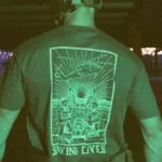 Cotton T-shirt with Saving Lives artwork showing soldiers in action, holding a stretcher during a tense medevac moment with a helicopter descending nearby.