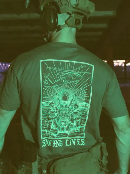 Cotton T-shirt with Saving Lives artwork showing soldiers in action, holding a stretcher during a tense medevac moment with a helicopter descending nearby.