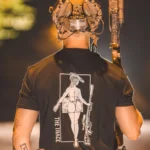 black tshirt from The Trace featuring a girl carrying a sniper weapon.