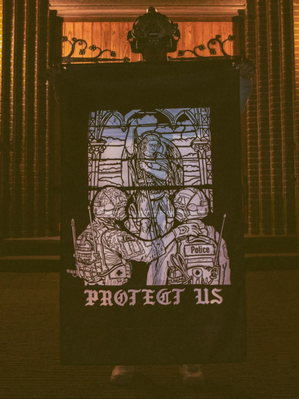 mog-x-trace-black-white-flag the trace apparel collection featuring a military and a police guy standing in front of a tinted window that displays saint michael the protector
