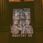 the trace apparel collection featuring a military and a police guy standing in front of a tinted window that displays saint michael the protector