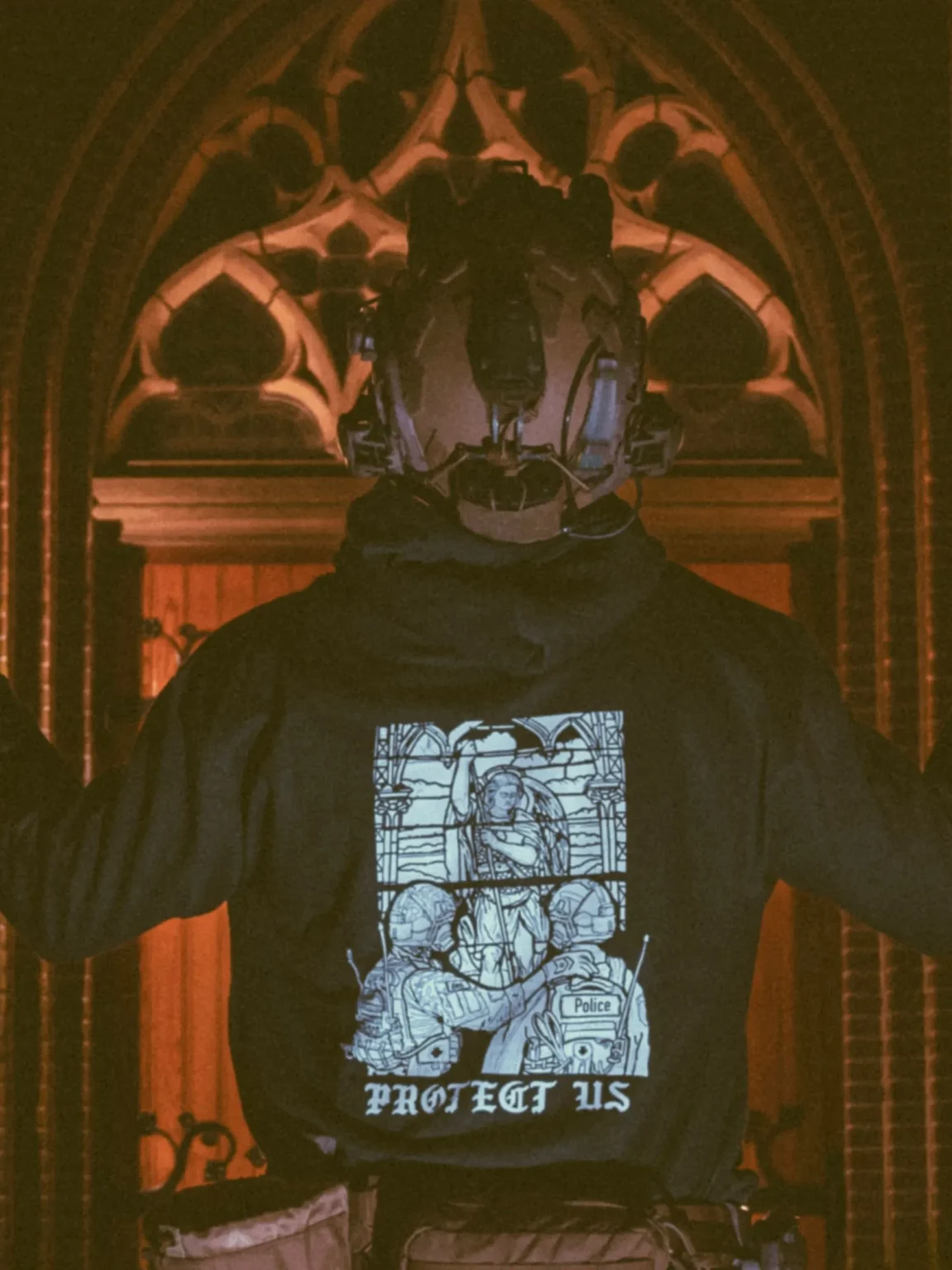 mog-x-trace-charcoal-hoodie-back the trace apparel collection featuring a military and a police guy standing in front of a tinted window that displays saint michael the protector
