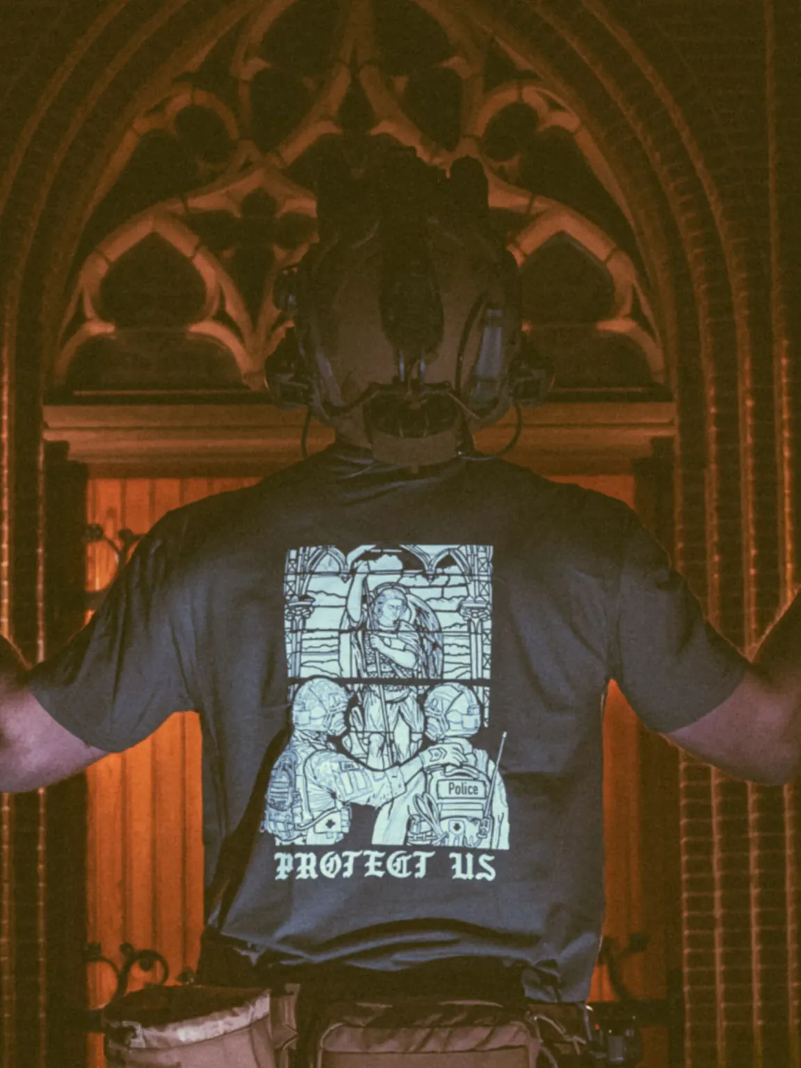 mog-x-trace-charcoal-shirt-back-cropped the trace apparel collection featuring a military and a police guy standing in front of a tinted window that displays saint michael the protector