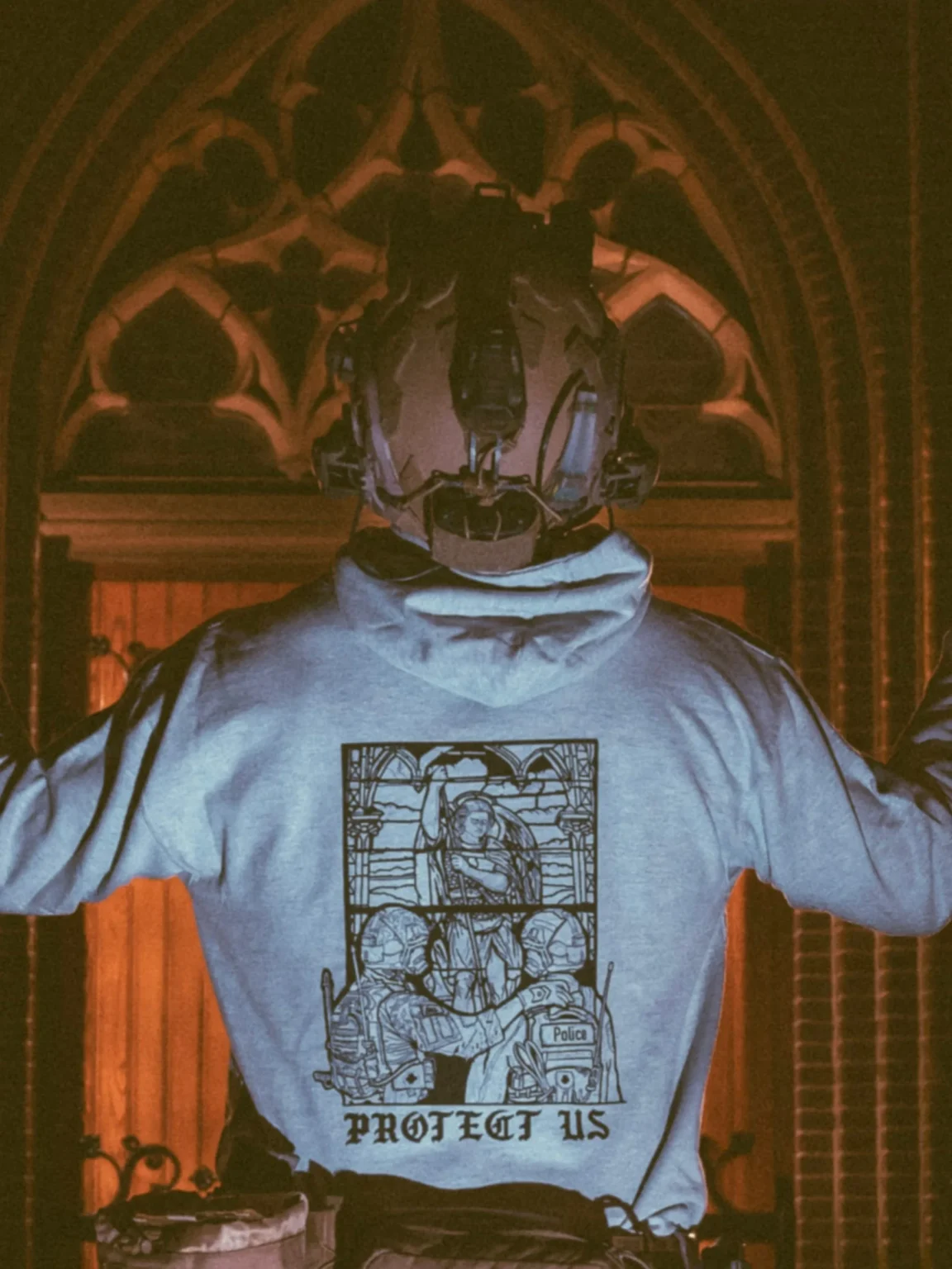 collection de vêtements The Trace avec un militaire et un policier devant une vitre teintée affichant saint Michel le protecteur