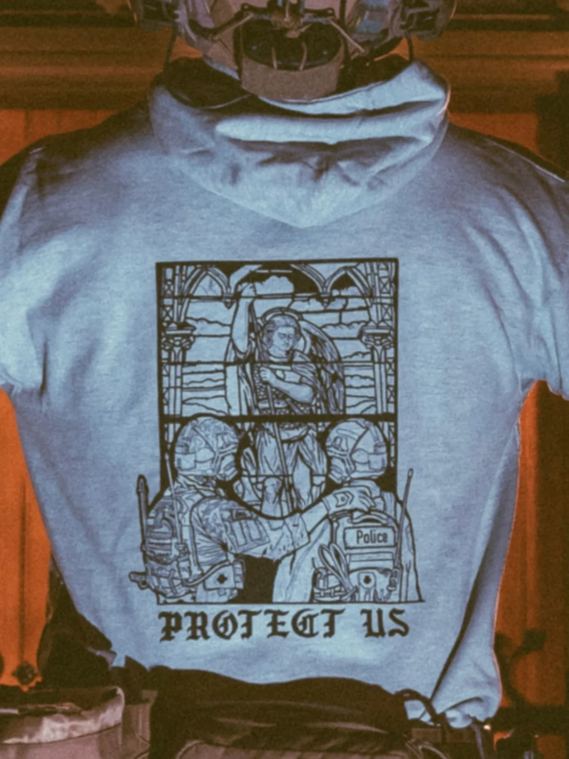collection de vêtements The Trace avec un militaire et un policier devant une vitre teintée affichant saint Michel le protecteur
