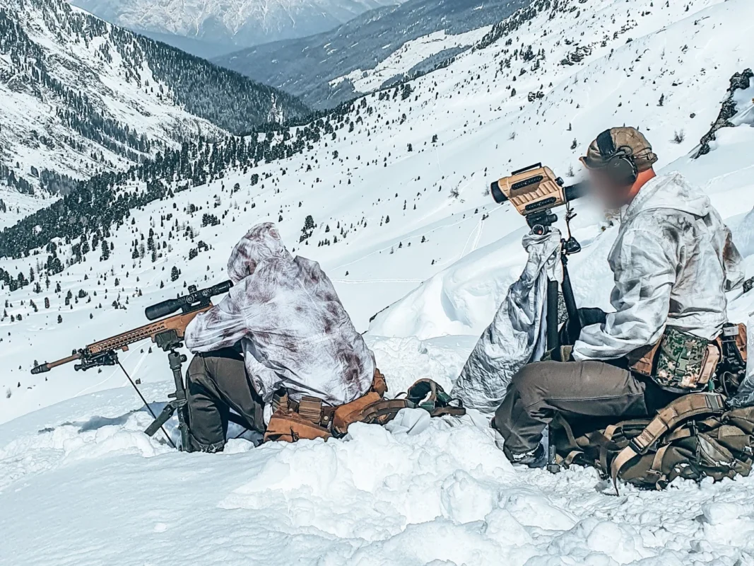 Dutch sniper and spotter in snow camouflage overlooking an alpine valley in Austria
