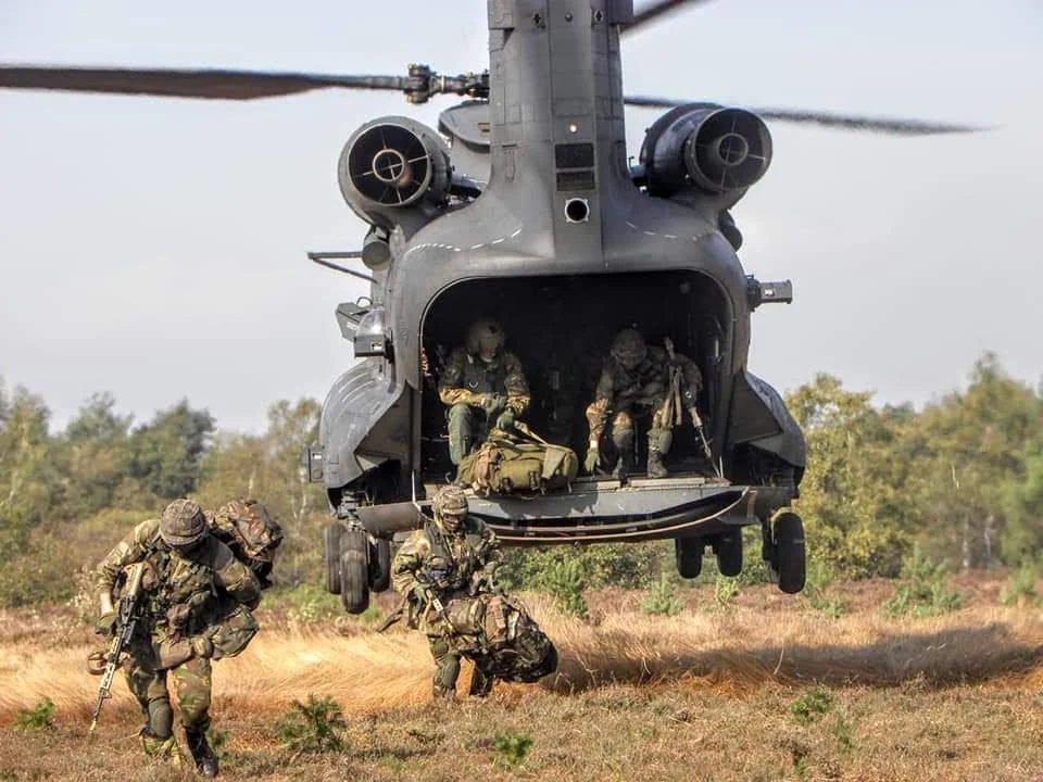 Dutch airmobile recruits stepping off the ramp of a Chinook helicopter onto heathland during training