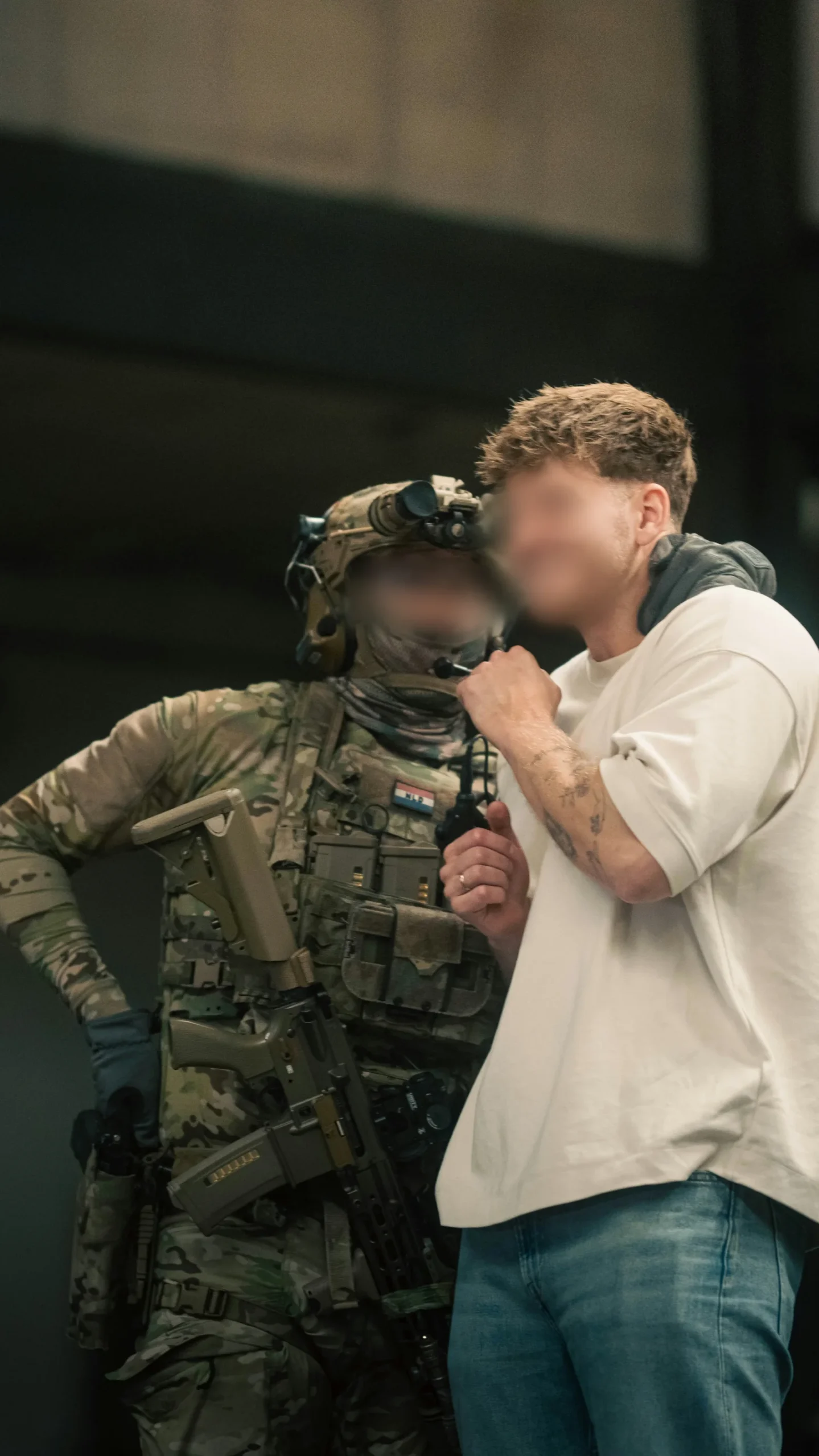 Martijn in civilian clothes standing beside a fully equipped operator with night vision