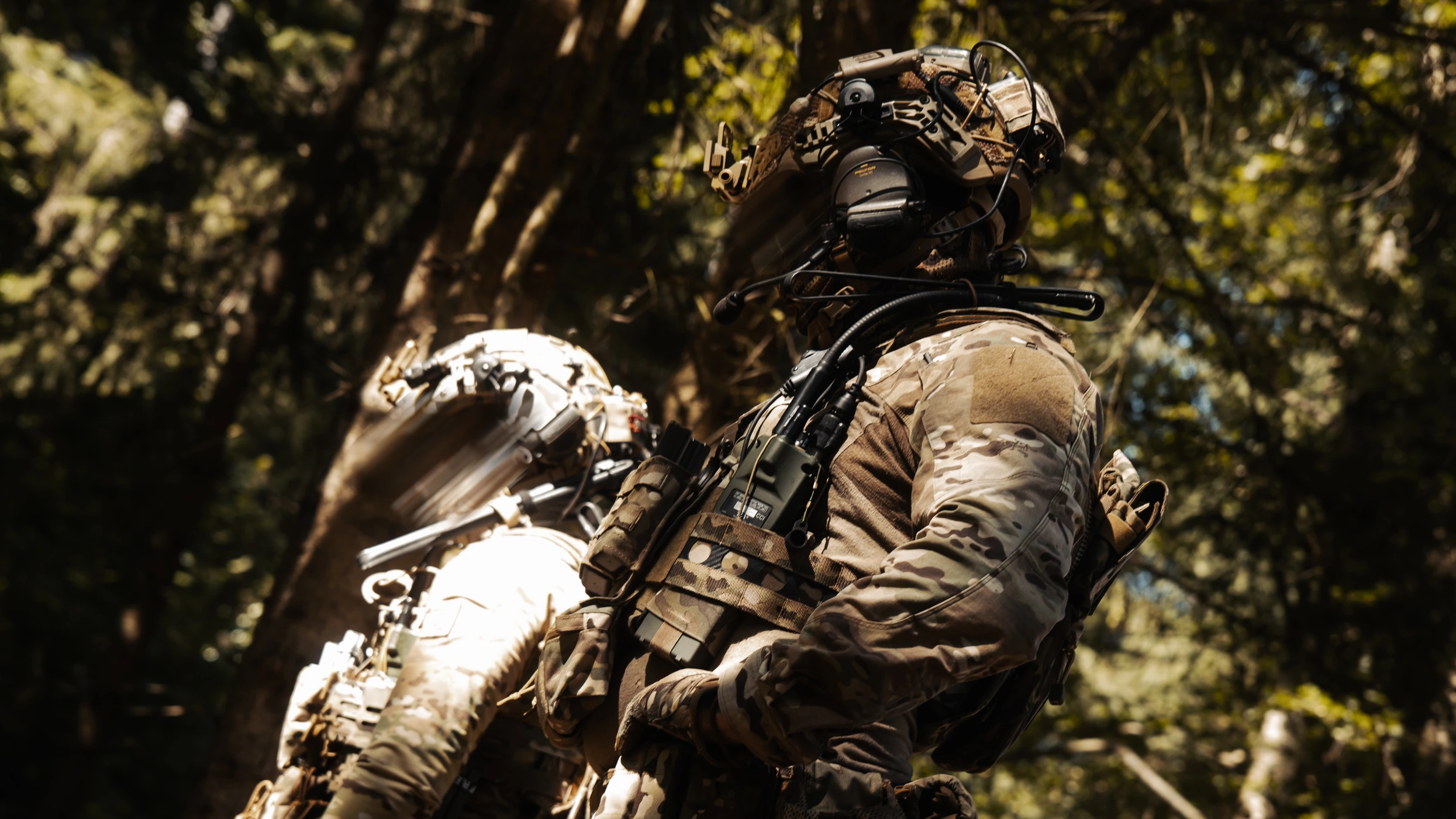 Two operators in multicam moving through sunlit woodland