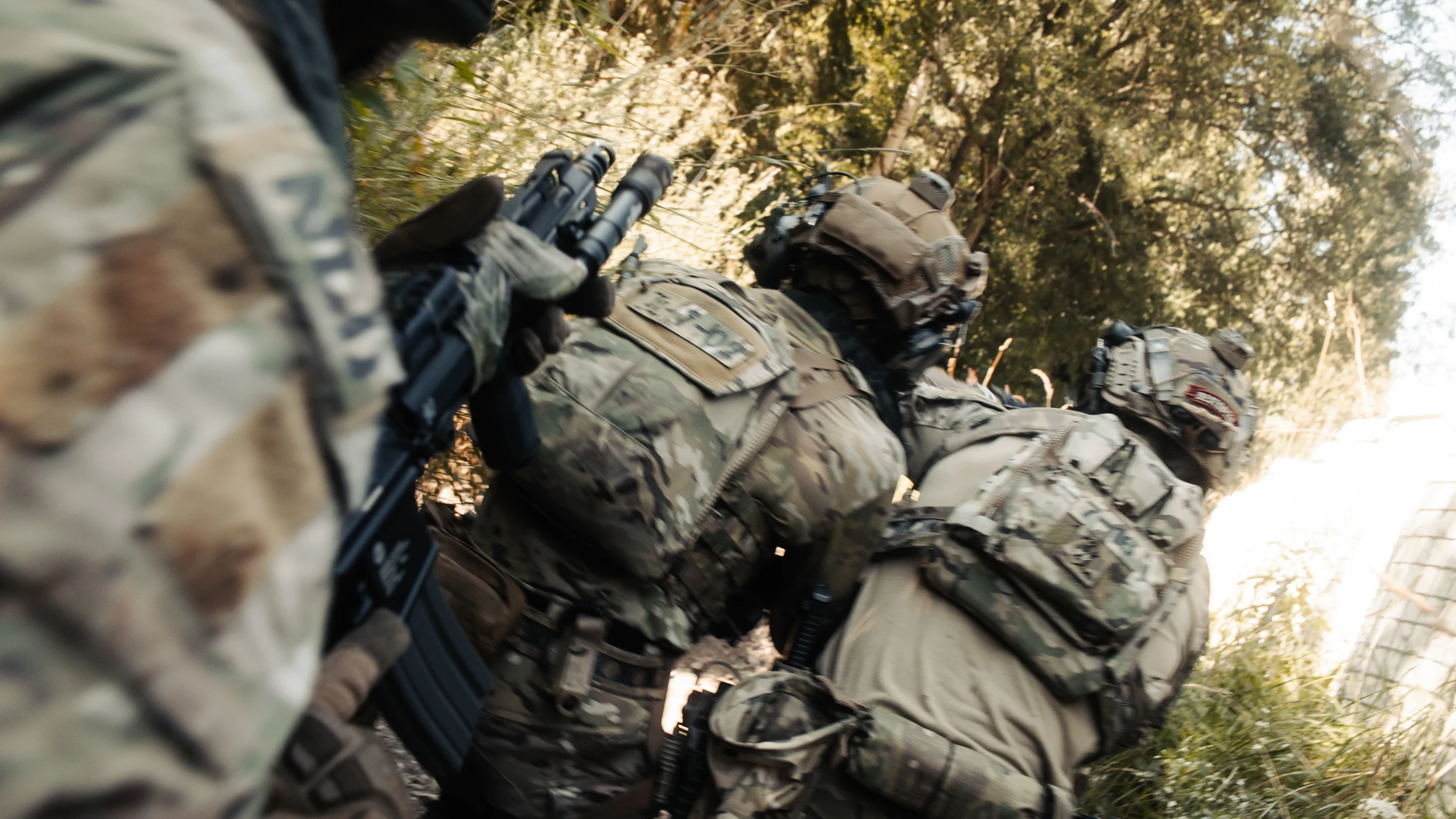 Stack of operators seen from a low angle, rifles up, moving forward together